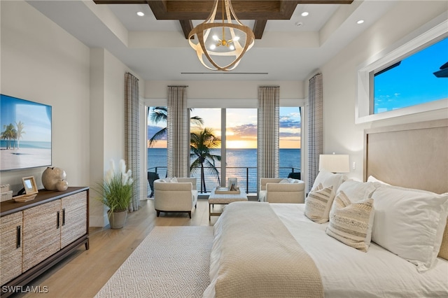 bedroom featuring an inviting chandelier, light hardwood / wood-style flooring, and a water view