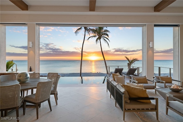 tiled dining space with a water view, beam ceiling, and a wealth of natural light