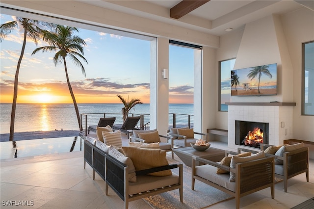 tiled living room with beamed ceiling, a wealth of natural light, and a fireplace