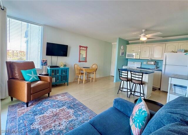 living room featuring light hardwood / wood-style floors, ceiling fan, and sink