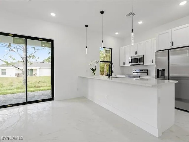 kitchen featuring hanging light fixtures, sink, white cabinets, and stainless steel appliances