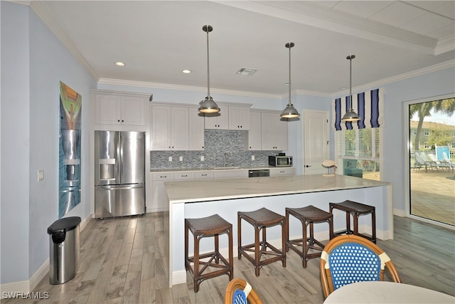 kitchen with a large island, stainless steel appliances, hanging light fixtures, and light hardwood / wood-style floors