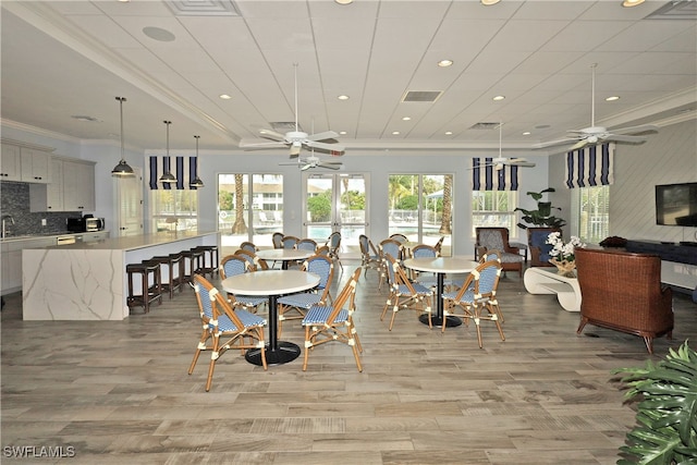 dining space with a wealth of natural light, sink, light wood-type flooring, and ornamental molding