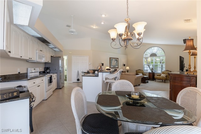 dining space with light tile patterned floors, an inviting chandelier, and lofted ceiling