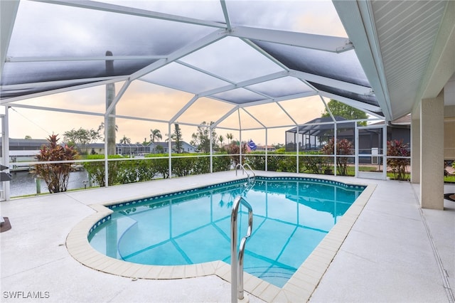 pool at dusk with glass enclosure, a water view, and a patio