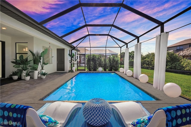 pool at dusk with a lanai and a patio