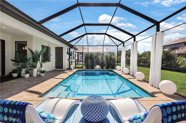 view of pool with a patio, glass enclosure, and a lawn