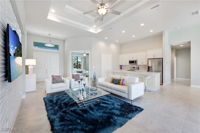 living room featuring a towering ceiling, a raised ceiling, and ceiling fan