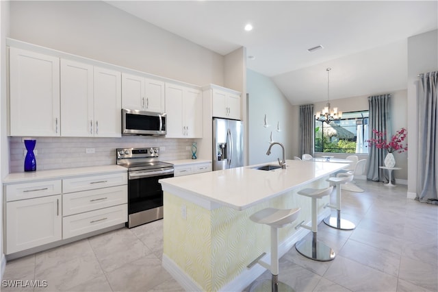 kitchen featuring appliances with stainless steel finishes, a kitchen island with sink, sink, white cabinetry, and lofted ceiling