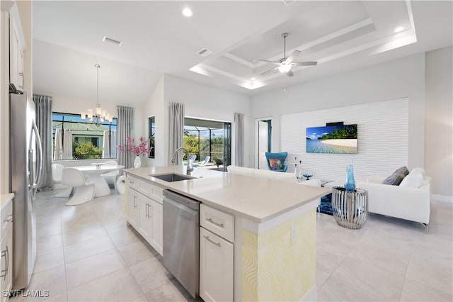 kitchen with sink, a tray ceiling, a kitchen island with sink, white cabinets, and appliances with stainless steel finishes