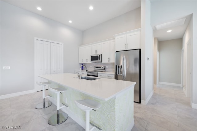 kitchen with white cabinets, appliances with stainless steel finishes, a center island with sink, and sink