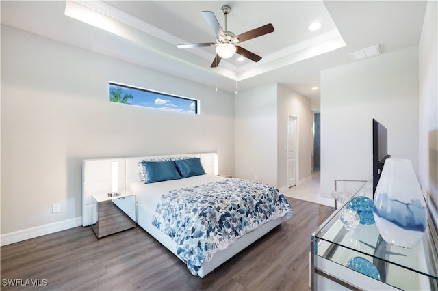 bedroom featuring hardwood / wood-style flooring, ceiling fan, and a raised ceiling