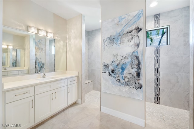 bathroom with a tile shower and vanity