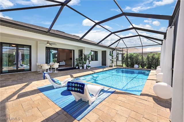 view of pool featuring a patio, glass enclosure, and ceiling fan