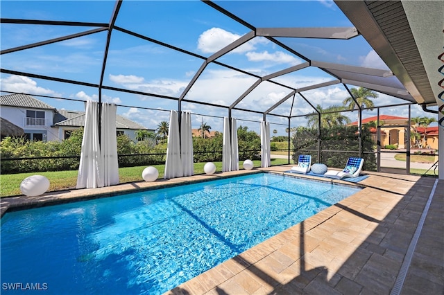 view of pool with glass enclosure and a patio area