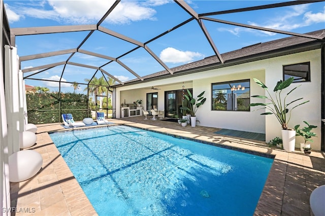 view of swimming pool with glass enclosure, ceiling fan, and a patio