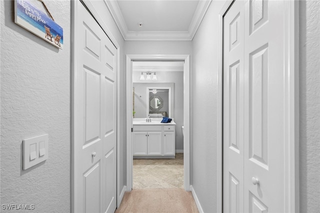 corridor with ornamental molding, light colored carpet, and sink