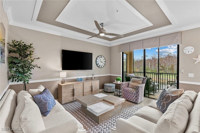 living room featuring ceiling fan, a raised ceiling, and crown molding