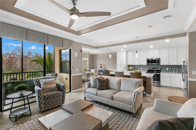 living room with sink, a raised ceiling, ceiling fan, and crown molding