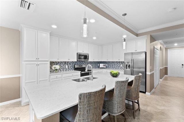 kitchen with white cabinets, stainless steel appliances, sink, and an island with sink