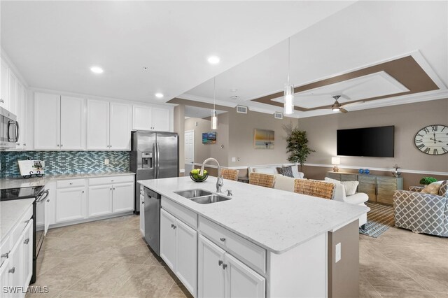 kitchen with sink, appliances with stainless steel finishes, a kitchen island with sink, white cabinets, and pendant lighting