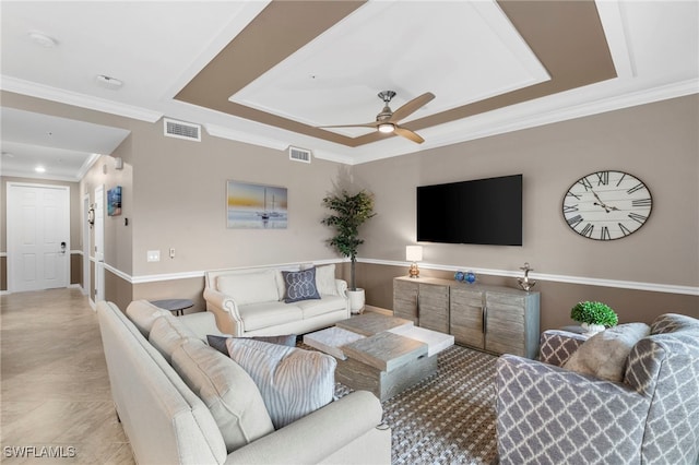 living room featuring ceiling fan, a tray ceiling, and ornamental molding