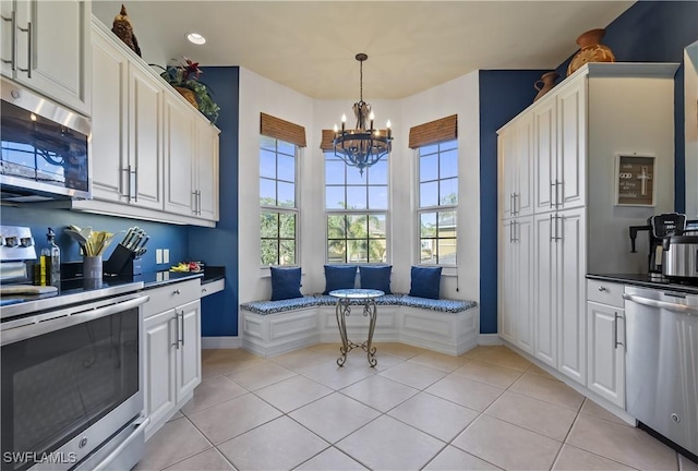 kitchen featuring white cabinetry, light tile patterned flooring, stainless steel appliances, and a notable chandelier