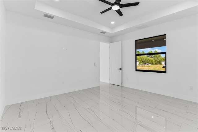 unfurnished room featuring ceiling fan and a raised ceiling