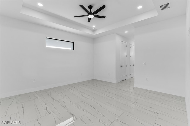 spare room featuring a tray ceiling and ceiling fan