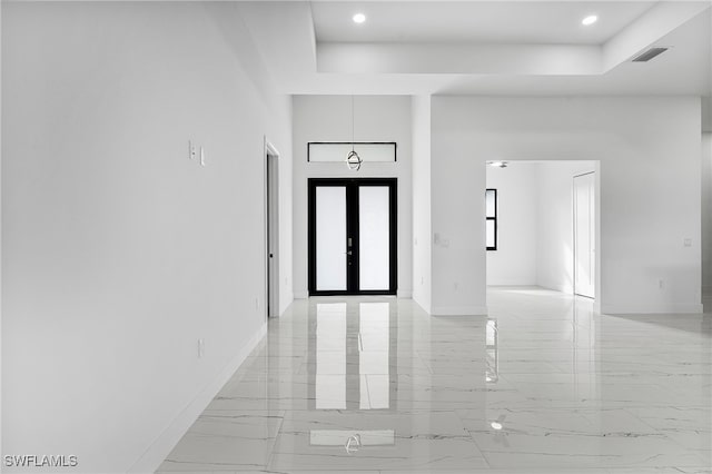 hallway featuring a high ceiling, french doors, and a tray ceiling