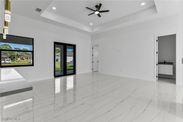 unfurnished room with a high ceiling, a tray ceiling, french doors, and ceiling fan