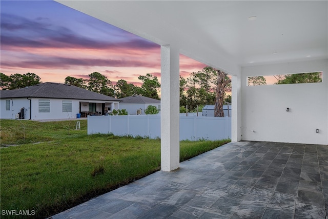 patio terrace at dusk featuring a yard