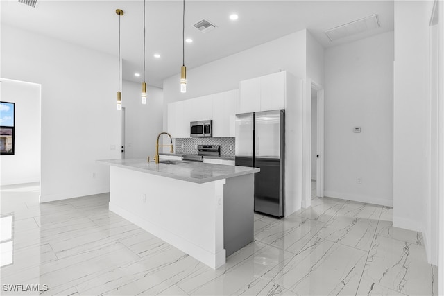 kitchen featuring stainless steel appliances, a center island with sink, sink, tasteful backsplash, and decorative light fixtures