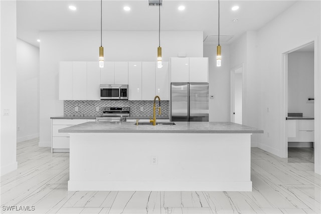 kitchen with pendant lighting, white cabinets, a center island with sink, and stainless steel appliances