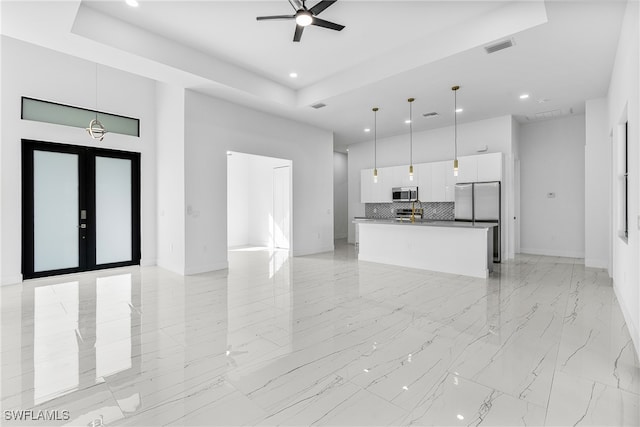 unfurnished living room featuring french doors, ceiling fan, and a raised ceiling