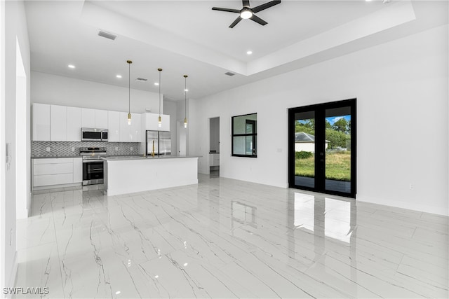 unfurnished living room featuring ceiling fan and a raised ceiling