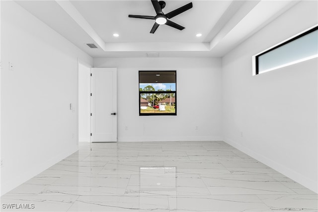 spare room with ceiling fan and a raised ceiling