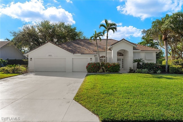 view of front of property with a garage, driveway, a tiled roof, a front lawn, and stucco siding