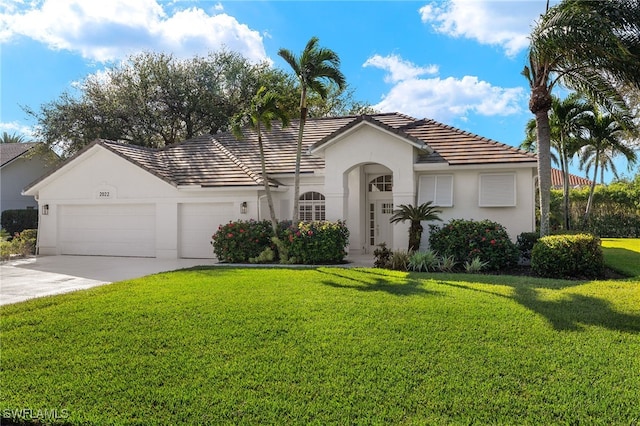 view of front of property featuring a tile roof, a front yard, stucco siding, concrete driveway, and an attached garage