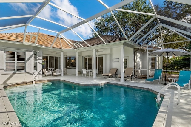 view of pool featuring glass enclosure, ceiling fan, and a patio area