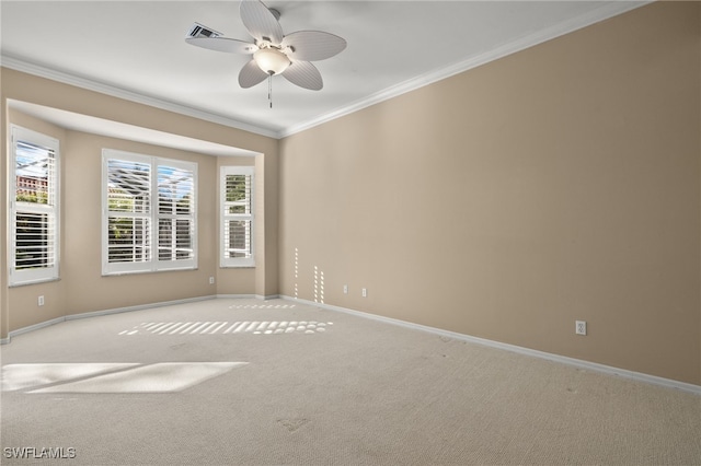 carpeted spare room featuring baseboards, visible vents, ceiling fan, and crown molding
