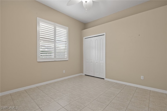 unfurnished bedroom featuring baseboards, ceiling fan, light tile patterned flooring, and a closet