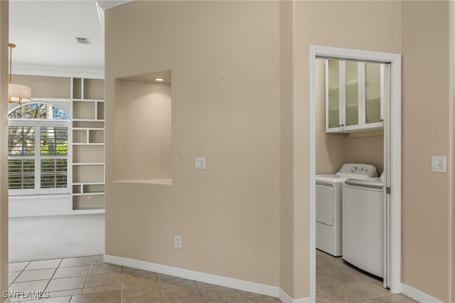 clothes washing area with crown molding, light tile patterned flooring, cabinets, and independent washer and dryer