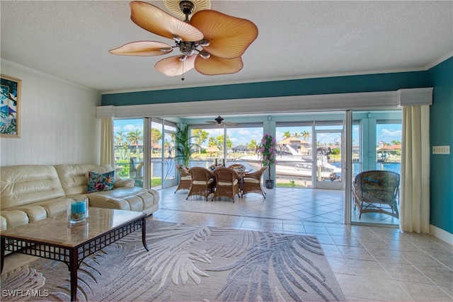 tiled living room with ceiling fan, a textured ceiling, and ornamental molding