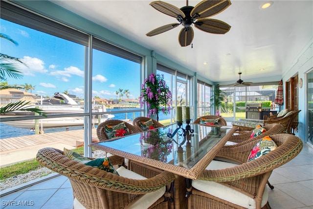 sunroom / solarium with ceiling fan and a water view