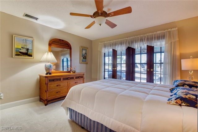 bedroom with a textured ceiling, french doors, light carpet, and ceiling fan