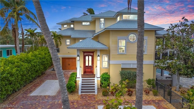 view of front of home with a garage, a shingled roof, fence, decorative driveway, and stucco siding