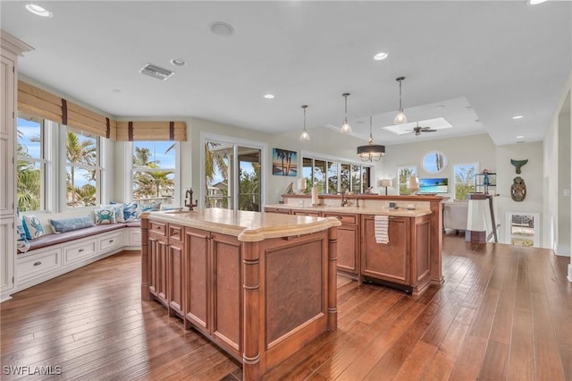 kitchen with visible vents, white cabinetry, a center island, brown cabinetry, and decorative light fixtures