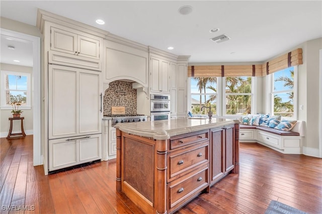 kitchen with dark wood-style floors, tasteful backsplash, a wealth of natural light, and a center island