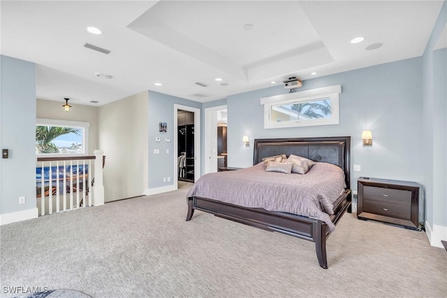 bedroom with light carpet, a tray ceiling, visible vents, and baseboards